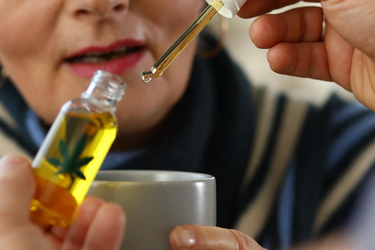 Close-up of a person holding a CBD oil tincture bottle while preparing to add drops to a beverage, symbolizing the premium CBD products available at CBD Malta. Perfect for relaxation, wellness, and everyday balance.